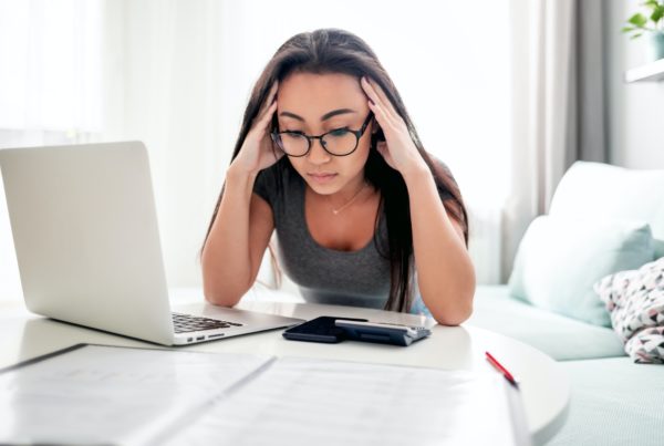 Desperate and worried asian woman calculating taxes bills at home